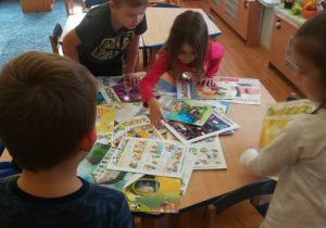 Dzieci wybierają czasopismo „Świerszczyk” spośród wielu gazet rozłożonych na stoliku.